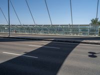 a truck driving across a bridge near a street corner near buildings and a bridge with many cables