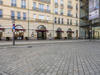 people walking on sidewalk in front of an old hotel building with large windows and doors