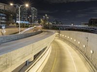 an urban freeway with cars and a light tower in the distance behind it at night