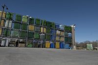 a parking lot with many large crates piled to each other with blue skies in the background