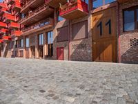 a person sitting on a bench in a cobblestone walkway outside a building,