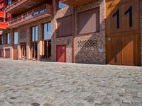 a person sitting on a bench in a cobblestone walkway outside a building,