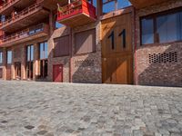 a person sitting on a bench in a cobblestone walkway outside a building,