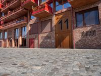 a person sitting on a bench in a cobblestone walkway outside a building,