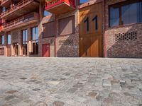 a person sitting on a bench in a cobblestone walkway outside a building,