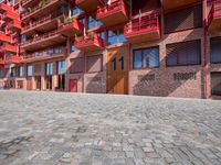 a person sitting on a bench in a cobblestone walkway outside a building,