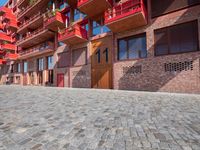 a person sitting on a bench in a cobblestone walkway outside a building,