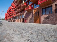 a person sitting on a bench in a cobblestone walkway outside a building,