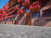 a person sitting on a bench in a cobblestone walkway outside a building,