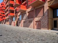 a person sitting on a bench in a cobblestone walkway outside a building,