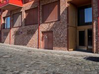 a person sitting on a bench in a cobblestone walkway outside a building,