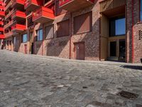 a person sitting on a bench in a cobblestone walkway outside a building,