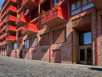 a person sitting on a bench in a cobblestone walkway outside a building,