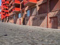 a person sitting on a bench in a cobblestone walkway outside a building,