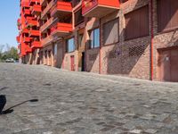 a person sitting on a bench in a cobblestone walkway outside a building,