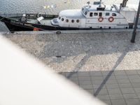 large white boat next to dock with people on it's side, by a dock