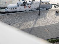 large white boat next to dock with people on it's side, by a dock