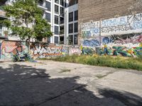 an empty area with graffiti on the side of it and a woman riding a motorcycle down it