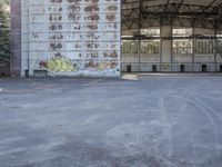 an empty, dilapidated parking area has lots of graffiti on the walls and doors of the building