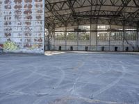 an empty, dilapidated parking area has lots of graffiti on the walls and doors of the building