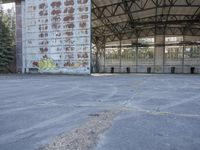 an empty, dilapidated parking area has lots of graffiti on the walls and doors of the building