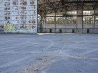 an empty, dilapidated parking area has lots of graffiti on the walls and doors of the building