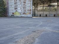 an empty, dilapidated parking area has lots of graffiti on the walls and doors of the building