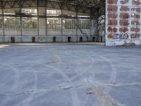 an empty, dilapidated parking area has lots of graffiti on the walls and doors of the building