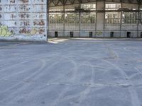 an empty, dilapidated parking area has lots of graffiti on the walls and doors of the building