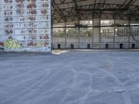 an empty, dilapidated parking area has lots of graffiti on the walls and doors of the building