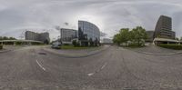 a street view from a fish eye lens with buildings in the background and trees in the distance