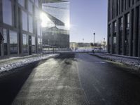 a street near a tall building with some lights at sunset in winter time in the middle of it