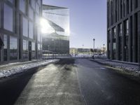 a street near a tall building with some lights at sunset in winter time in the middle of it