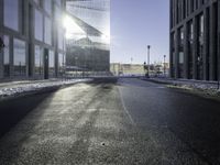 a street near a tall building with some lights at sunset in winter time in the middle of it