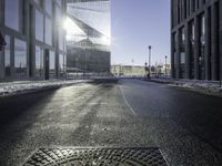 a street near a tall building with some lights at sunset in winter time in the middle of it