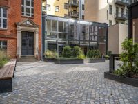 an empty parking lot with plants in the ground and on the side of the building, there is an enclosed area and windows