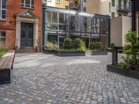 an empty parking lot with plants in the ground and on the side of the building, there is an enclosed area and windows