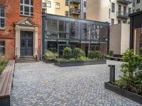 an empty parking lot with plants in the ground and on the side of the building, there is an enclosed area and windows