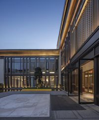 there is an empty courtyard in the building with its lights on at twilight time and many windows open