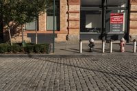 a picture of a building near a brick sidewalk and some fire hydrants with a red sign saying public space is open