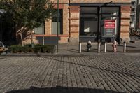 a picture of a building near a brick sidewalk and some fire hydrants with a red sign saying public space is open