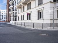 an empty street with buildings in the background and two stop signs at a corner that point towards a row of brick