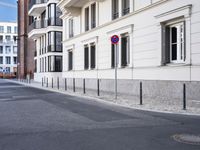 an empty street with buildings in the background and two stop signs at a corner that point towards a row of brick