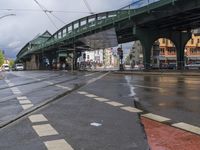 a bus is traveling down the road under some bridges on the sidewalk in the rain