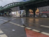 a bus is traveling down the road under some bridges on the sidewalk in the rain