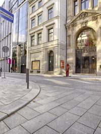 a street with many windows and various buildings in the background with a bicycle racket on a pole next to it