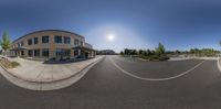 a fish eye lens lens shot a building in a parking lot, and an intersection with parked cars