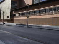 a city street with a building and sidewalk in front of it and a couple people sitting on the curb of the road with a stop sign