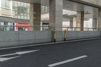 white arrows painted on the side of an empty road next to tall buildings, viewed out of a moving car window