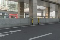 white arrows painted on the side of an empty road next to tall buildings, viewed out of a moving car window